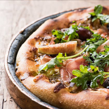 Photo of delicious CRU pizza, with a focus on the crust on the edges, rustic serving tray and wood grain table.